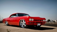 Красный Chevrolet Impala отбрасывает четкую тень от палящего солнца